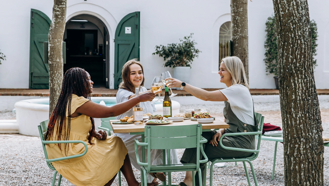Freundinnen genießen ein Brunch im Hof eines südafrikanischen Weinguts