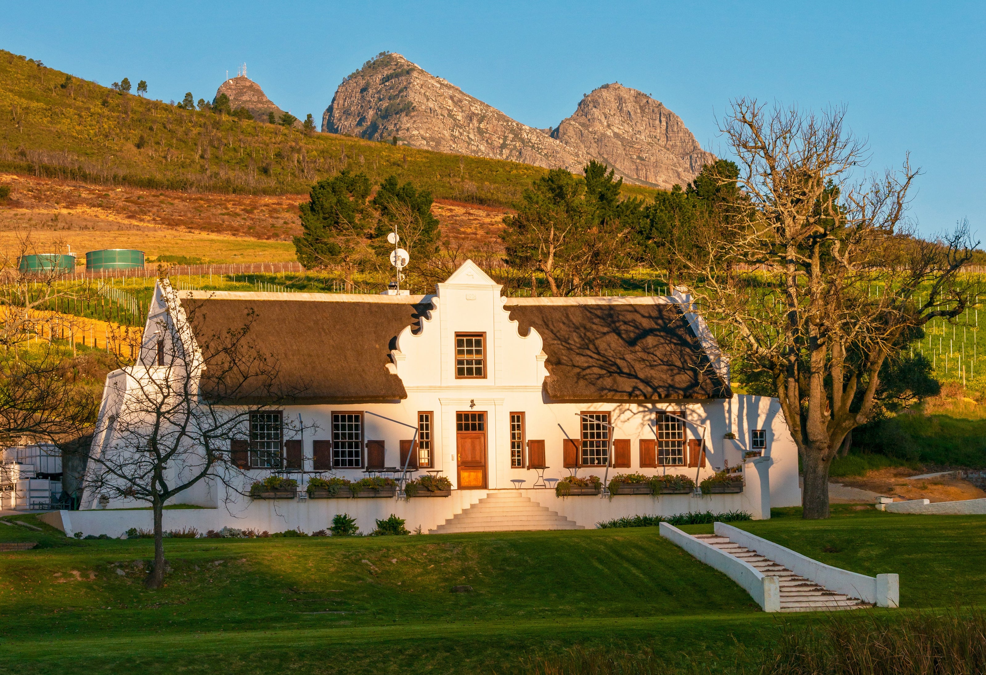 Das historische Weingut Lievland bei Sonnenuntergang am Fuße eines Bergs in Stellenbosch