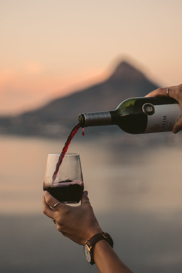 Rotwein wird in ein Glas gefüllt, im Hintergrund der Lions Head bei Sonnenuntergang
